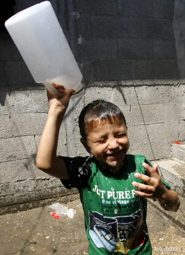 A Palestinian child enjoys herself with water during hot weather and high temperature in the southern Gaza Strip town of Rafah on July 02, 2012. Photo by Eyad Al Baba