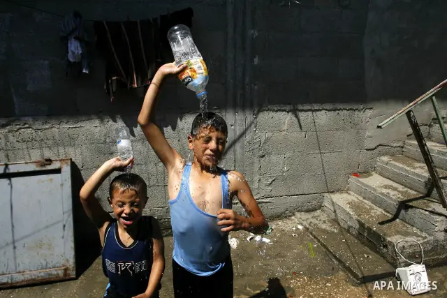 Palestinian children enjoy themselves with water during hot weather and high temperature in the southern Gaza Strip town of Rafah on July 02, 2012. Photo by Eyad Al Baba