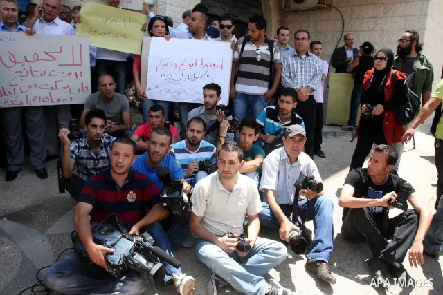 Palestinian Photojournalists hold banners and cameras outside the office of the Palestinian Interior Ministry in the West Bank city of Ramallah, July 03, 2012. Journalists protested against the assault by Palestinian pol...