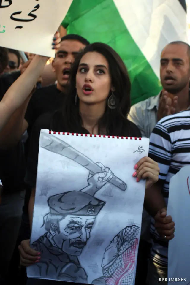 Palestinian demonstrators hold a national flag in the West Bank city of Ramallah on July 3, 2012 to protest against the violent dispersal of two similar rallies over the weekend. The demonstration was called by the "Pale...