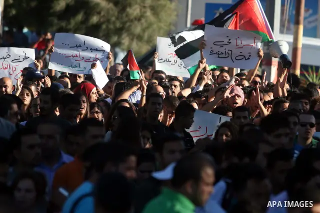 Palestinian demonstrators hold a national flag in the West Bank city of Ramallah on July 3, 2012 to protest against the violent dispersal of two similar rallies over the weekend. The demonstration was called by the "Pale...