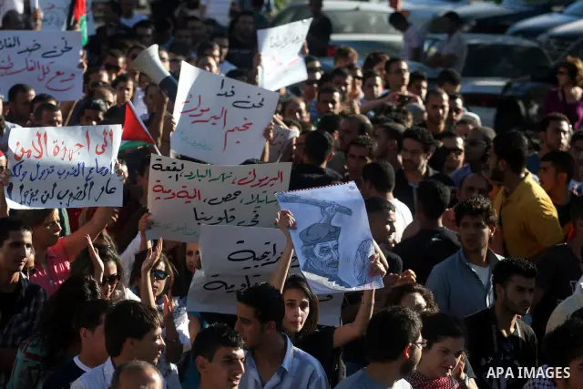 Palestinian demonstrators hold a national flag in the West Bank city of Ramallah on July 3, 2012 to protest against the violent dispersal of two similar rallies over the weekend. The demonstration was called by the "Pale...