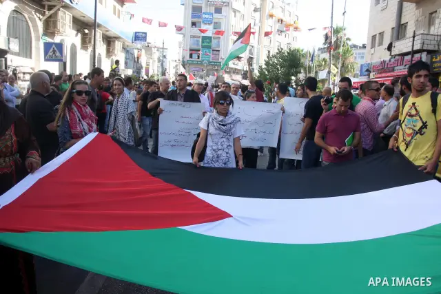 Palestinian demonstrators hold a national flag in the West Bank city of Ramallah on July 3, 2012 to protest against the violent dispersal of two similar rallies over the weekend. The demonstration was called by the "Pale...
