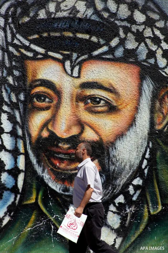 A Palestinian man walks past a mural depicting late Hamas spiritual leader Sheikh Ahmed Yassin (L) and late Palestinian leader Yasser Arafat (R) in Gaza City on July 4, 2012. Arafat, who died in 2004, was poisoned by pol...