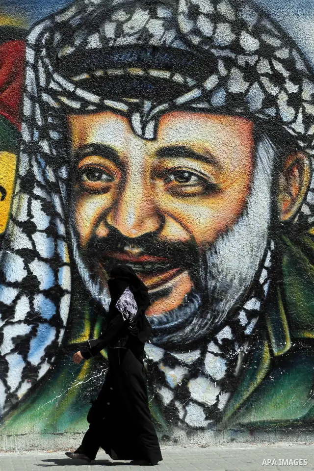 A Palestinian woman walks past a mural depicting late Hamas spiritual leader Sheikh Ahmed Yassin (L) and late Palestinian leader Yasser Arafat (R) in Gaza City on July 4, 2012. Arafat, who died in 2004, was poisoned by p...