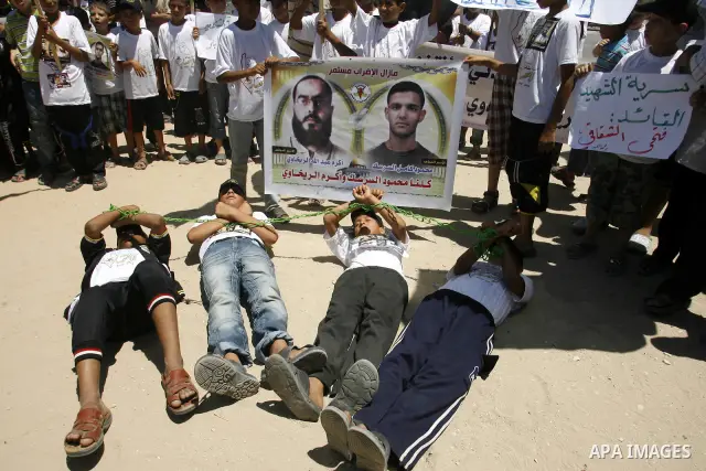 Palestinian boys hold pictures of Palestinian prisoners in the Palestinian Authority jails during a demonstration demands to release them, in the southern Gaza Strip town of Rafah on July 05, 2012. Photo by Eyad Al Baba