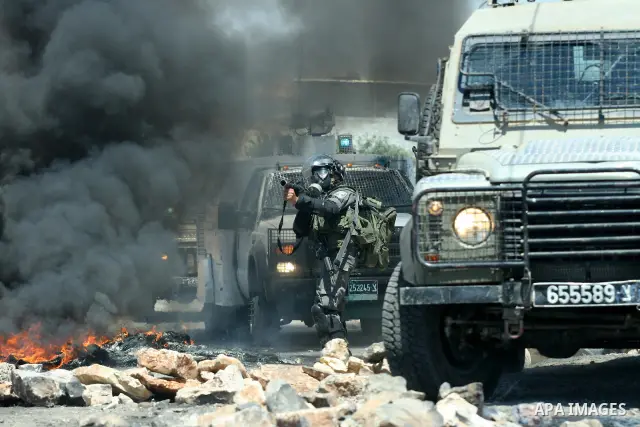 An Israeli border policeman fires teargas towards Palestinian demonstrators during a protest against the expansion of the nearby Jewish settlement of Kdumim, in the northern West Bank village of Kufr Qaddum, on 06 July 2...