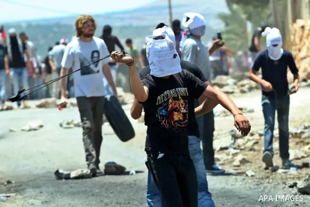Palestinians demonstrators throw stones towards Israeli border police during a protest against the expansion of the nearby Jewish settlement of Kdumim, in the northern West Bank village of Kufr Qaddum, on 06 July 2012. P...