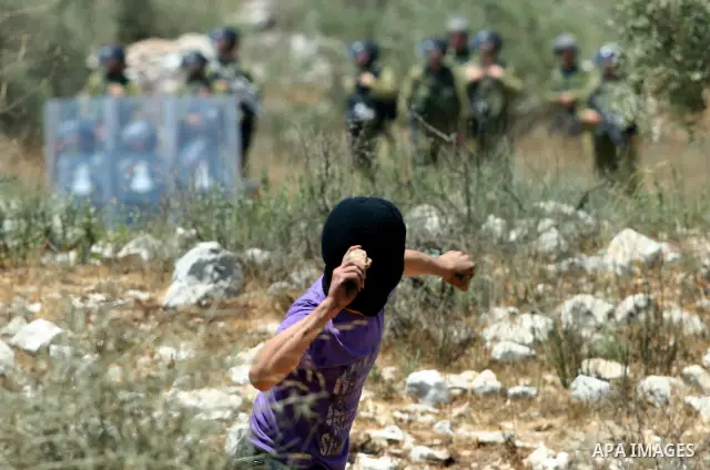A Palestinian demonstrator throws stones towards Israeli border police during a protest against the expansion of the nearby Jewish settlement of Kdumim, in the northern West Bank village of Kufr Qaddum, on 06 July 2012....