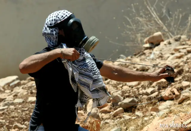 A Palestinian demonstrator throws stones towards Israeli border police during a protest against the expansion of the nearby Jewish settlement of Kdumim, in the northern West Bank village of Kufr Qaddum, on 06 July 2012....