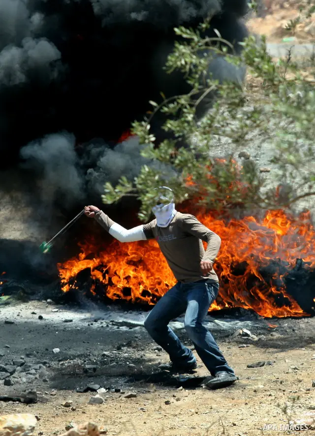 A Palestinian demonstrator throws stones towards Israeli border police during a protest against the expansion of the nearby Jewish settlement of Kdumim, in the northern West Bank village of Kufr Qaddum, on 06 July 2012....