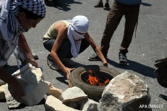 Palestinians protesters burn a tire during clashes with Israeli soldiers following a weekly protest against a nearby Jewish settlement, in the West Bank village of Nabi Saleh, near Ramallah July 6, 2012. Photo by Issam R...