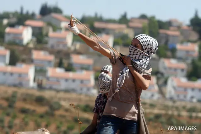 A Palestinian protester fires a stone from a slingshot towards Israeli soldiers during clashes at a weekly protest against a nearby Jewish settlement, in the West Bank village of Nabi Saleh, near Ramallah July 6, 2012. P...