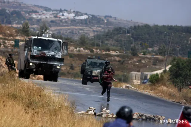 A Palestinian woman waves a Palestinian flag in front of a truck spraying foul smelling water during clashes with Israeli soldiers at a weekly protest against a nearby Jewish settlement, in the West Bank village of Nabi...