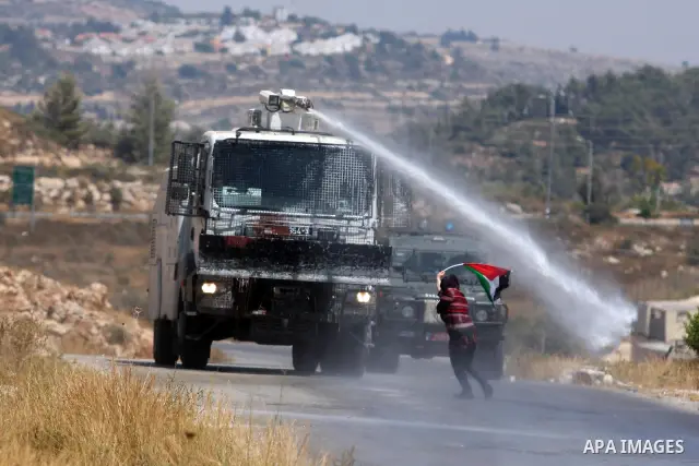 A Palestinian woman waves a Palestinian flag in front of a truck spraying foul smelling water during clashes with Israeli soldiers at a weekly protest against a nearby Jewish settlement, in the West Bank village of Nabi...