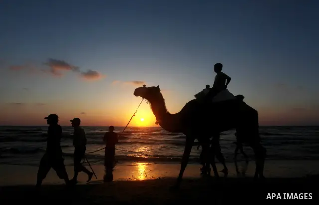 A Palestinian man rides a camel on the beach on their week-end in the Mediterranean port of Gaza on July 06, 2012. Photo by Ashraf Amra