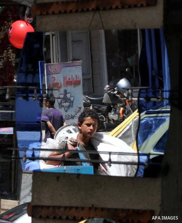 Palestinians are reflected in mirrors for sale as they walk through a traditional market in the refugee camp of Jabaliya, in the northern Gaza Strip, 07 July 2012 . Photo by Ashraf Amra