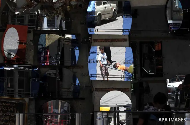 Palestinians are reflected in mirrors for sale as they walk through a traditional market in the refugee camp of Jabaliya, in the northern Gaza Strip, 07 July 2012 . Photo by Ashraf Amra
