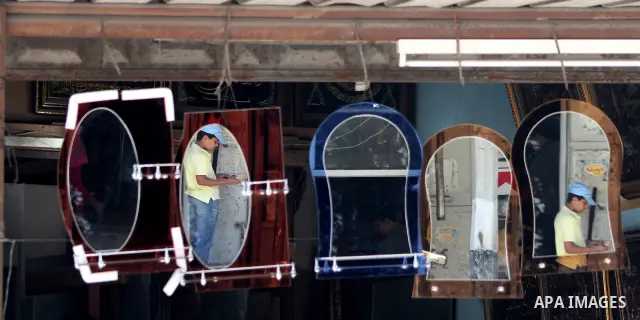 Palestinians are reflected in mirrors for sale as they walk through a traditional market in the refugee camp of Jabaliya, in the northern Gaza Strip, 07 July 2012 . Photo by Ashraf Amra