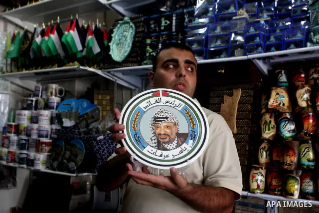 Palestinian vendor displays merchandise with pictures of the late Palestinian leader Yasser Arafat in Gaza City on July 7, 2012. Arafat, who died in 2004, was poisoned by polonium, according to the findings of laboratory...