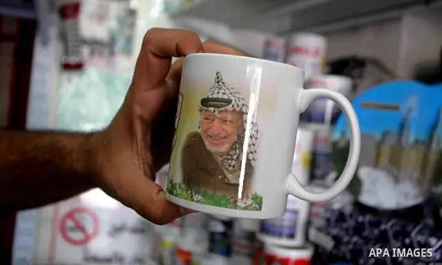 Palestinian vendor displays merchandise with pictures of the late Palestinian leader Yasser Arafat in Gaza City on July 7, 2012. Arafat, who died in 2004, was poisoned by polonium, according to the findings of laboratory...