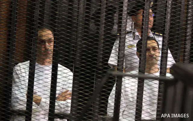 CAIRO, July 9, 2012 Gamal (L) and Alaa, sons of former Egyptian president Hosni Mubarak, are seen behind bars during their trial at the police academy in Cairo, July 9, 2012. Egypt's South Cairo Court on Monday started t...