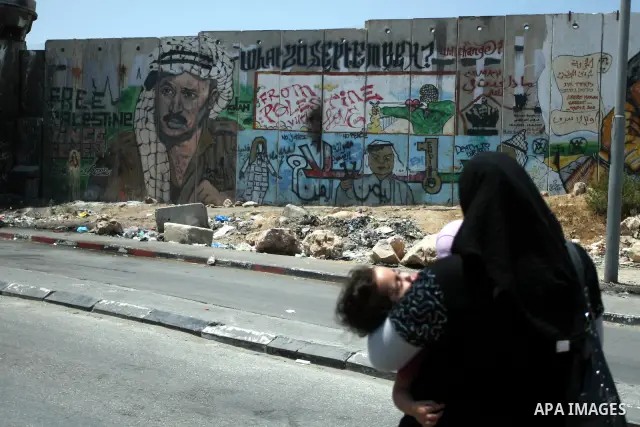 A Palestinian woman walks past the wall of separation between Ramallah and Jerusalem, July 9, 2012. Eight years ago, specifically in 2004, has taken International Court of Justice, judicial arm statute of the United Nati...