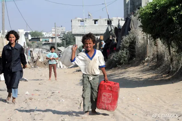 Palestinian children carry water bottles in Zeitoun neighborhood southern Gaza city on 09 July 2012. Photo by Ashraf Amra