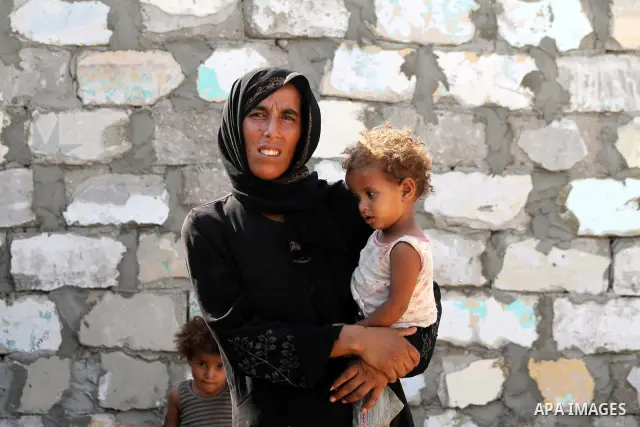 A Palestinian woman carries her child in front of her home in Zeitoun neighborhood southern Gaza city on 09 July 2012. Photo by Ashraf Amra
