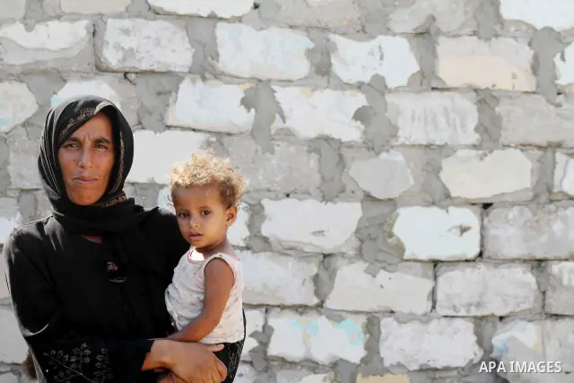 A Palestinian woman carries her child in front of her home in Zeitoun neighborhood southern Gaza city on 09 July 2012. Photo by Ashraf Amra