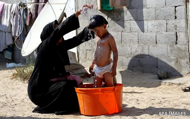 A Palestinian woman bathes her child in front of her home in Zeitoun neighborhood southern Gaza city on 09 July 2012. Photo by Ashraf Amra