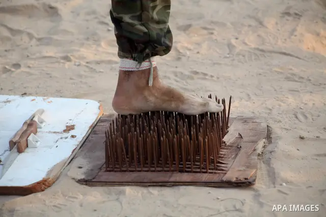 A Palestinian trainer stands on tapered nails during training in a summer camp organized by Hamas movement at Shati refugee camp in Gaza City July 10, 2012. Hamas movement organized dozens of summer camps for Palestinian...
