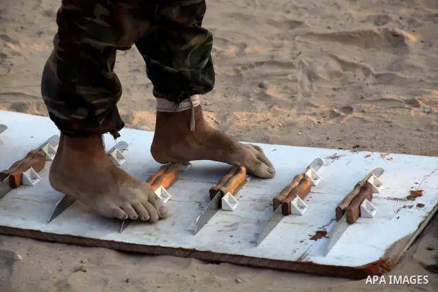 A Palestinian trainer walks on sharp knifes during training in a summer camp organized by Hamas movement at Shati refugee camp in Gaza City July 10, 2012. Hamas movement organized dozens of summer camps for Palestinian c...