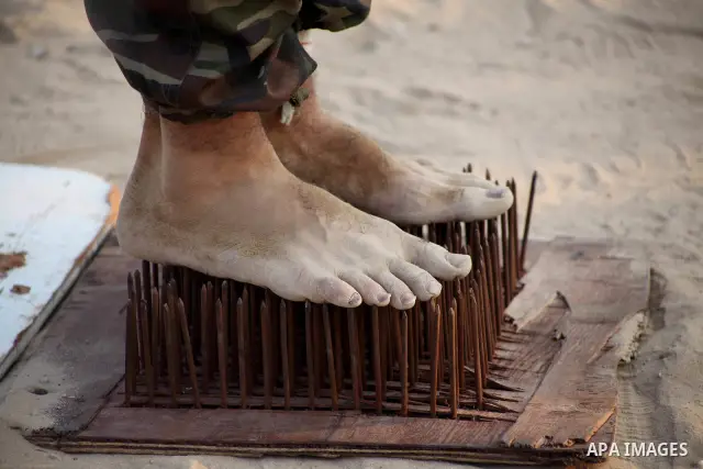 A Palestinian trainer stands on tapered nails during training in a summer camp organized by Hamas movement at Shati refugee camp in Gaza City July 10, 2012. Hamas movement organized dozens of summer camps for Palestinian...
