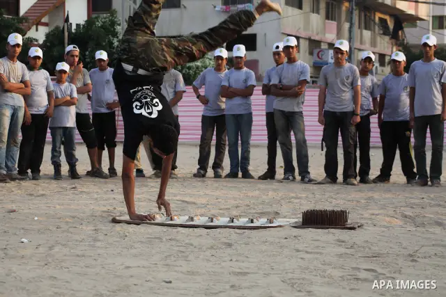 A Palestinian trainer walks on sharp knifes during training in a summer camp organized by Hamas movement at Shati refugee camp in Gaza City July 10, 2012. Hamas movement organized dozens of summer camps for Palestinian c...