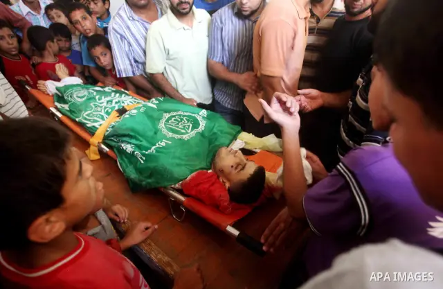 Palestinians mourn over the body of Hamas militant Mahmud Al-Heggi during his funeral in the Al Zaitun area in the east of Gaza city, 12 July 2012. Al Heggi was killed and others wounded after an Israeli air strike in AL...