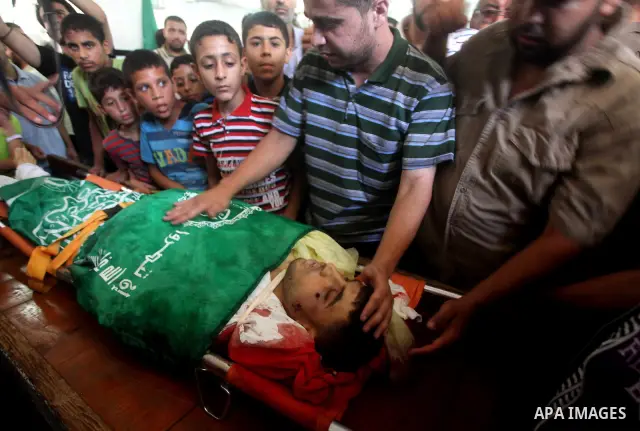 Palestinians mourn over the body of Hamas militant Mahmud Al-Heggi during his funeral in the Al Zaitun area in the east of Gaza city, 12 July 2012. Al Heggi was killed and others wounded after an Israeli air strike in AL...