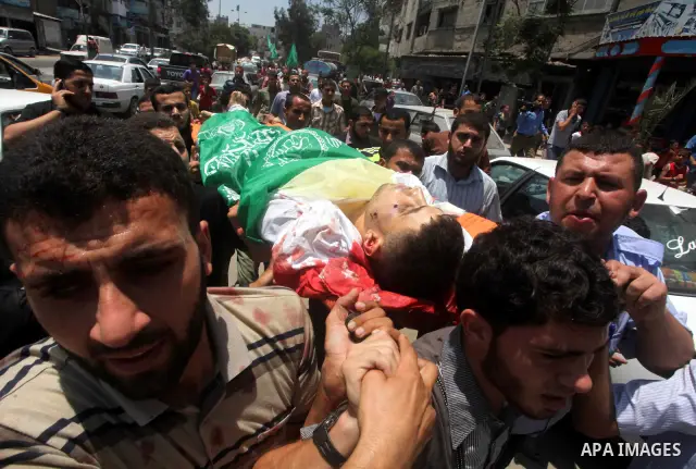 Palestinian mourners carry the body of Hamas militant Mahmud Al-Heggi during his funeral in the Al Zaitun area in the east of Gaza city, 12 July 2012. Al Heggi was killed and others wounded after an Israeli air strike in...
