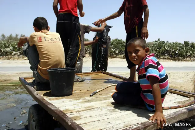 Palestinians wash their horse in the street during hot weather and high temperature in the southern Gaza Strip town of Rafah on July 12, 2012. Photo by Eyad Al Baba