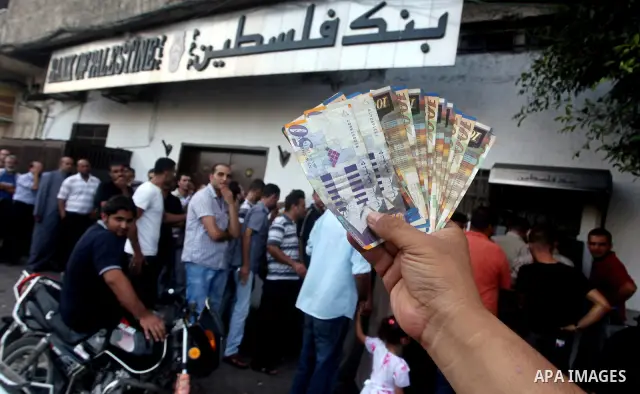 A Palestinian man displays his salary after withdrawing it from an automated teller machine of the Bank of Palestine in Gaza city on July 12, 2012. The Palestinian Authority announced that it will give only 60% of the sa...