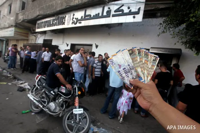 A Palestinian man displays his salary after withdrawing it from an automated teller machine of the Bank of Palestine in Gaza city on July 12, 2012. The Palestinian Authority announced that it will give only 60% of the sa...