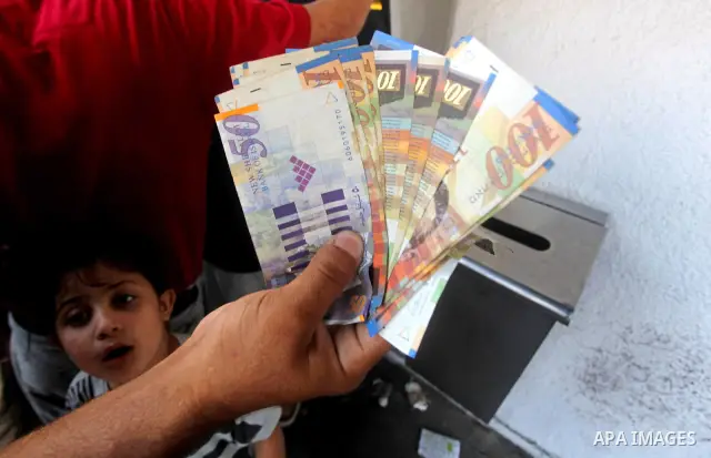 A Palestinian man displays his salary after withdrawing it from an automated teller machine of the Bank of Palestine in Gaza city on July 12, 2012. The Palestinian Authority announced that it will give only 60% of the sa...