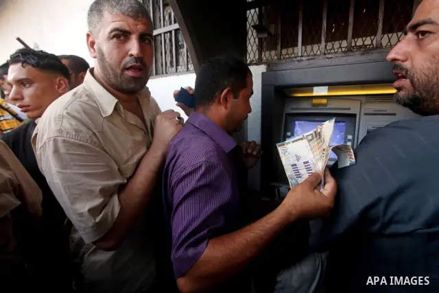 Palestinians queue to draw money from an automated teller machine of the Bank of Palestine in Gaza city on July 12, 2012. The Palestinian Authority announced that it will give only 60% of the salary due to the unpreceden...