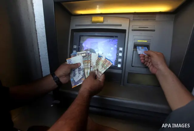 A Palestinian man displays his salary after withdrawing it from an automated teller machine of the Bank of Palestine in Gaza city on July 12, 2012. The Palestinian Authority announced that it will give only 60% of the sa...