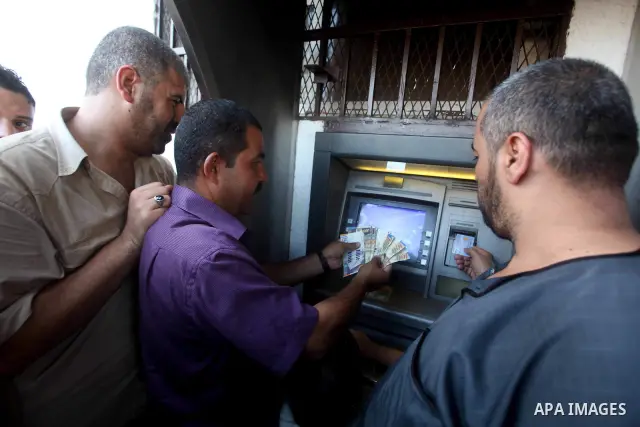 Palestinians queue to draw money from an automated teller machine of the Bank of Palestine in Gaza city on July 12, 2012. The Palestinian Authority announced that it will give only 60% of the salary due to the unpreceden...
