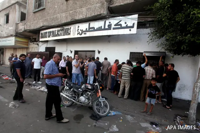 Palestinians queue to draw money from an automated teller machine of the Bank of Palestine in Gaza city on July 12, 2012. The Palestinian Authority announced that it will give only 60% of the salary due to the unpreceden...