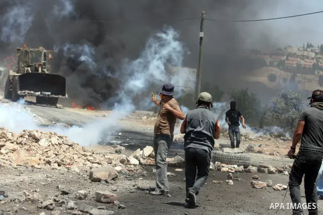 Palestinian protesters throw stones at Israeli truck during clashes following a weekly protest against the nearby Jewish settlement of Kdumim, in the West Bank village of Kufr Qaddum, near Nablus July 13, 2012. According...