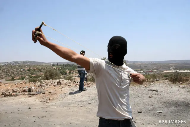 A Palestinian protester throws stones at Israeli truck during clashes following a weekly protest against the nearby Jewish settlement of Kdumim, in the West Bank village of Kufr Qaddum, near Nablus July 13, 2012. Accordi...