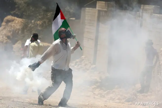 A palestinian protester throws back a gas canister at Israeli security forces during clashes following a weekly protest against the nearby Jewish settlement of Kdumim, in the West Bank village of Kufr Qaddum, near Nablus...