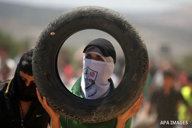 A Palestinian protester prepares a tire to burn it during clashes with Israeli security forces following a weekly protest against the nearby Jewish settlement of Kdumim, in the West Bank village of Kufr Qaddum, near Nabl...